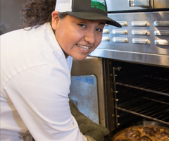 Young woman taking a pizza out of an oven